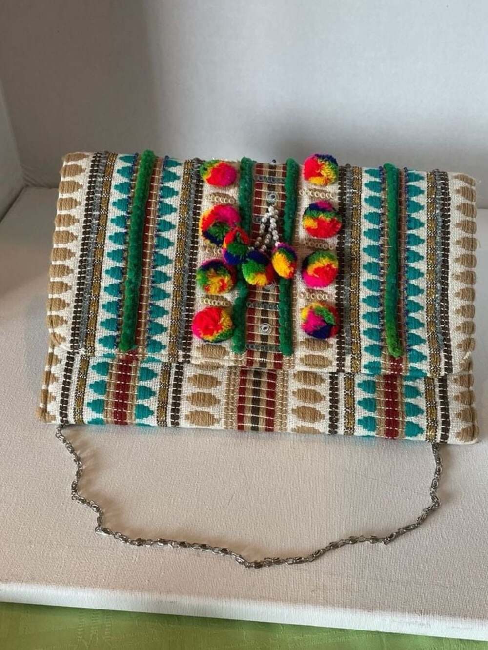 Charade Boho Embroidered Woven Clutch with Pom Poms and Chain Strap.